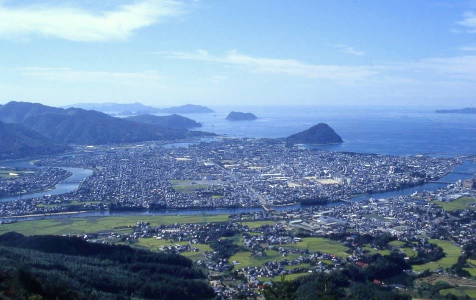 山口県萩市の市街地全景。日本海に面した城下町の町並みと、周囲の山々・海が調和する風景。