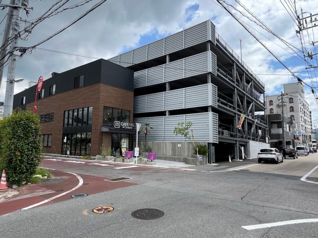 湯田温泉にあるカフェ「CAFESSS with È PRONTO」の外観と周辺の街並み。モダンな建物と通りの風景から、山口市街の発展やおしゃれな雰囲気が伝わる。