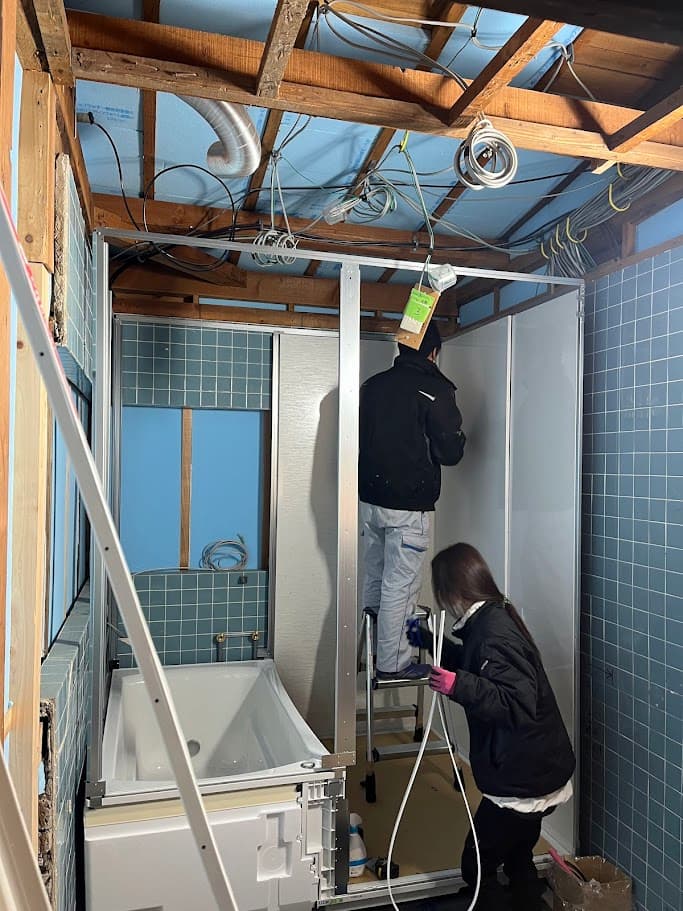 ユニットバスを設置するため、電気や配線工事を行う作業員の姿