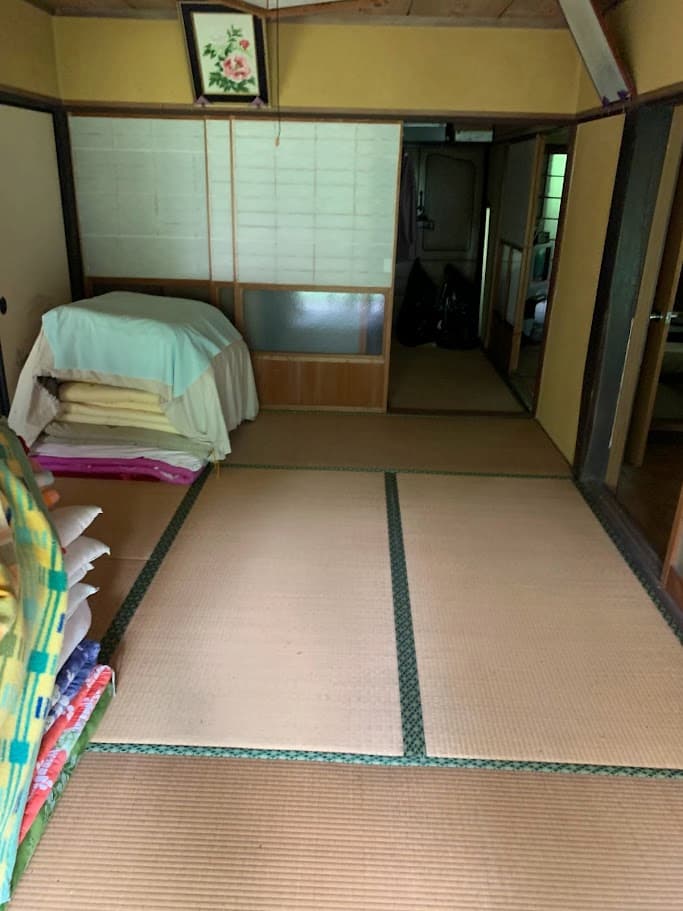 団が積まれたままの畳の部屋、古民家の内部
