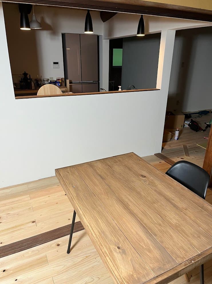 改修後のオープンキッチン。カウンター越しにダイニングと繋がり、梁や照明がモダンに調和した空間。