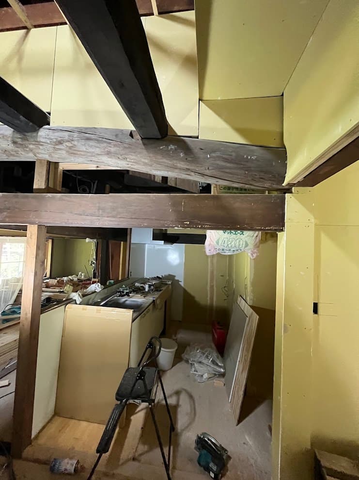 壁下地を貼り終え、古民家の太い梁を活かしたデザインに整えている最中のキッチン空間。