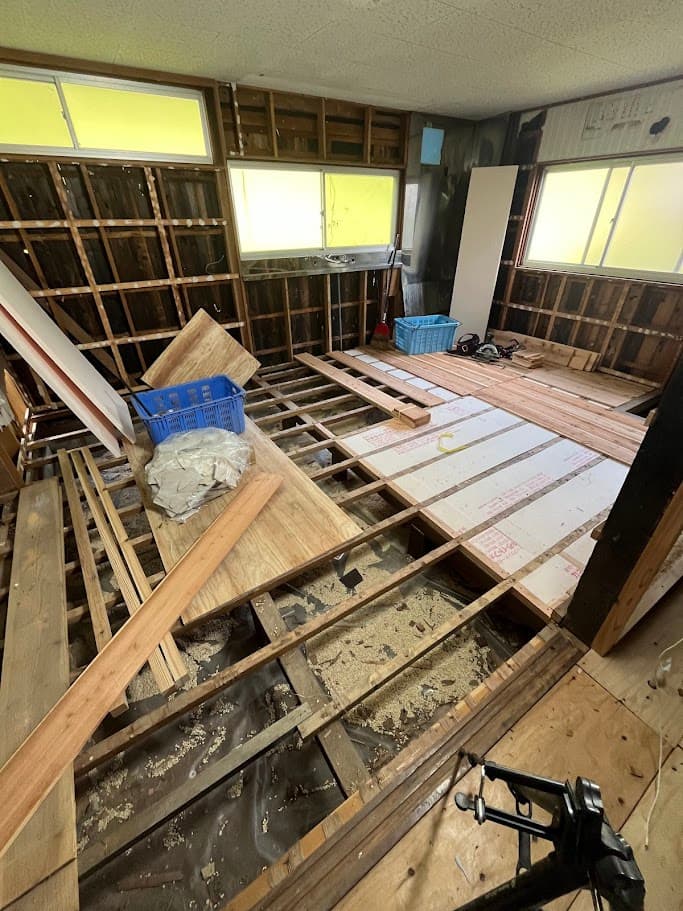 新しい木材で床下の骨組みを組み直している様子。強度と断熱性を高めるための施工段階。
