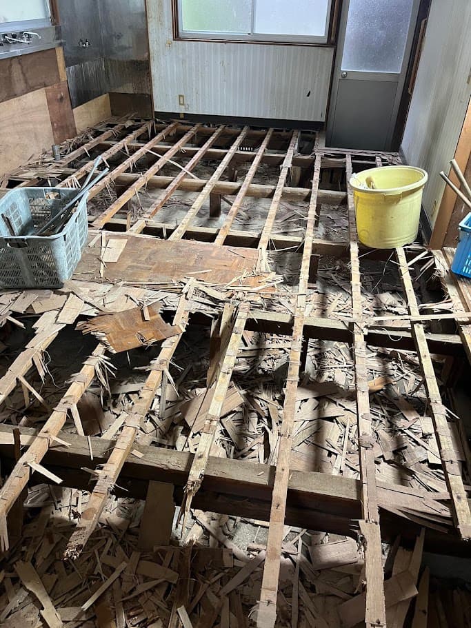 管理室の床を解体している途中。古い根太や木片が散乱し、基礎部分が露出している。