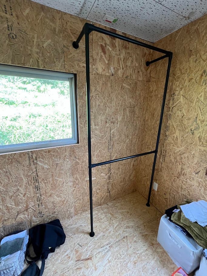 管理室に設置する黒のハンガーパイプを組み立てている様子。