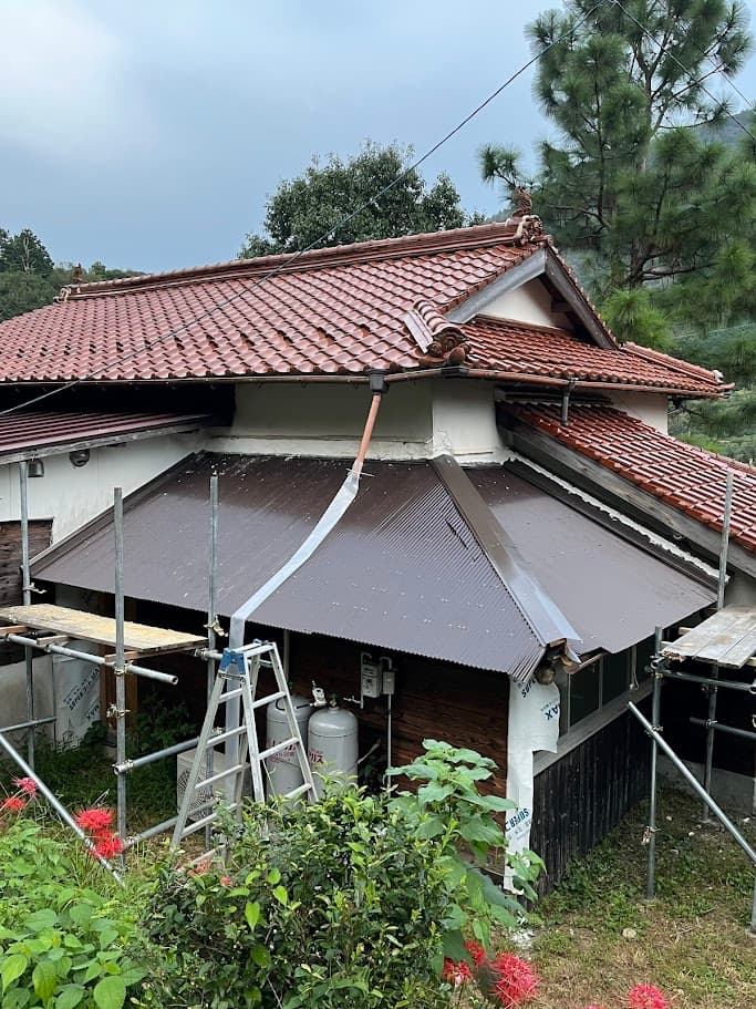 改修後の屋根外観。新しいトタン屋根と外壁が加わり、古民家の景観と調和する美しい仕上がり。