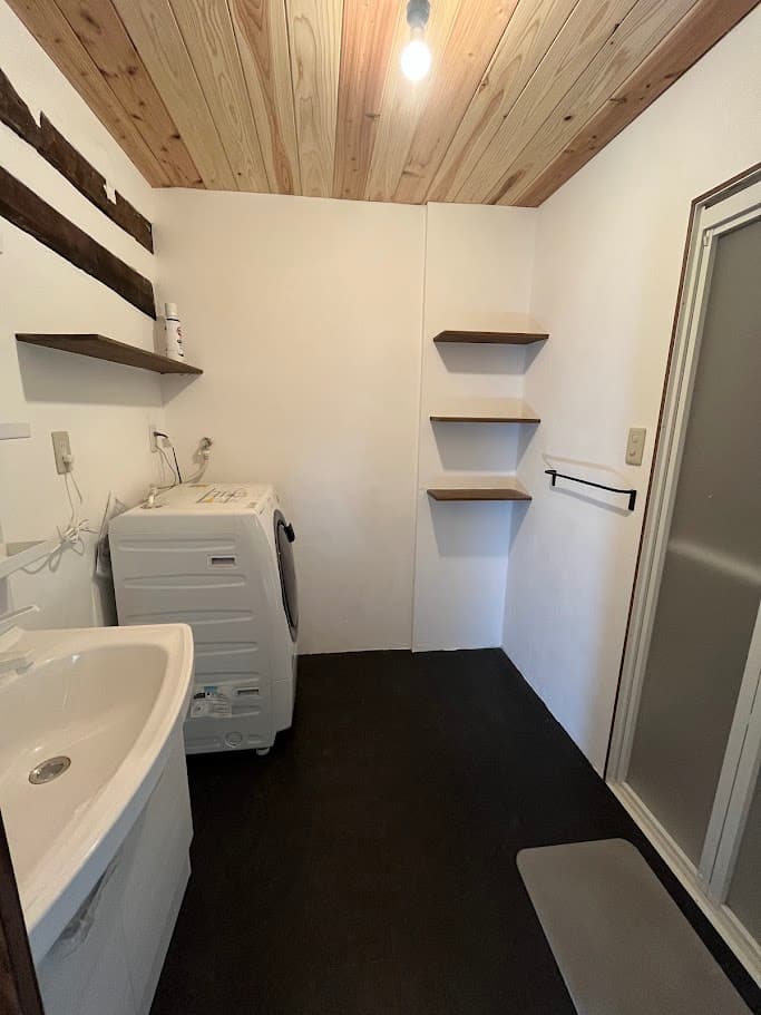 改修後の洗面所全体。無垢材の天井と白壁が明るく、収納棚と洗面台を新設した快適な空間。