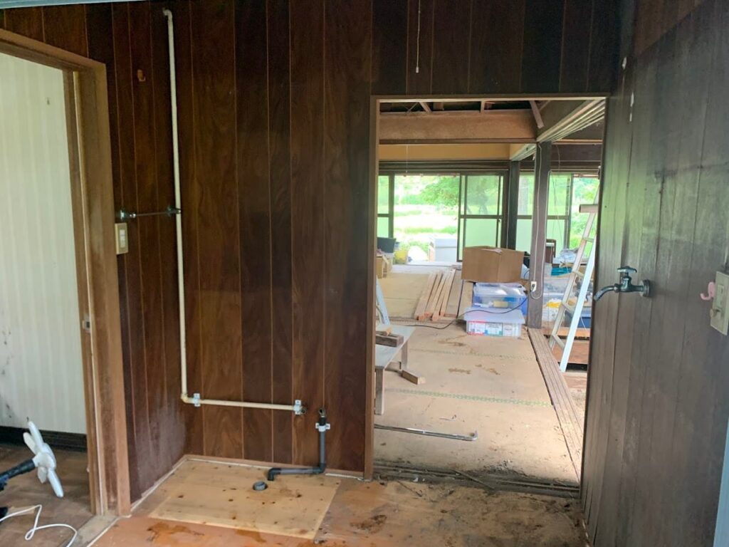 古い洗面台を撤去した後の洗面スペース。壁や配管が露出し、リフォーム前の準備段階。