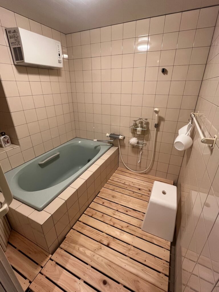 かんぬしの宿の浴室。タイル張りの浴槽とシャワー設備。