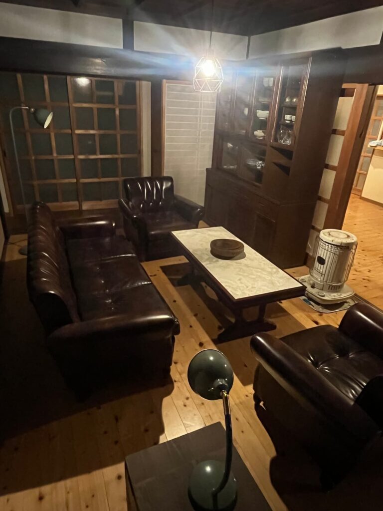 かんぬしの宿のリビングスペース。革張りソファとストーブのある落ち着いた空間。