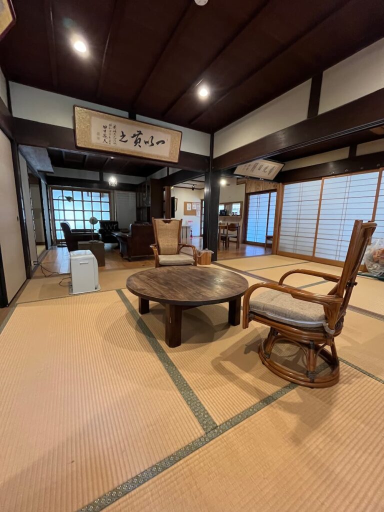 かんぬしの宿の畳スペース。丸テーブルと椅子が置かれたくつろぎ空間。