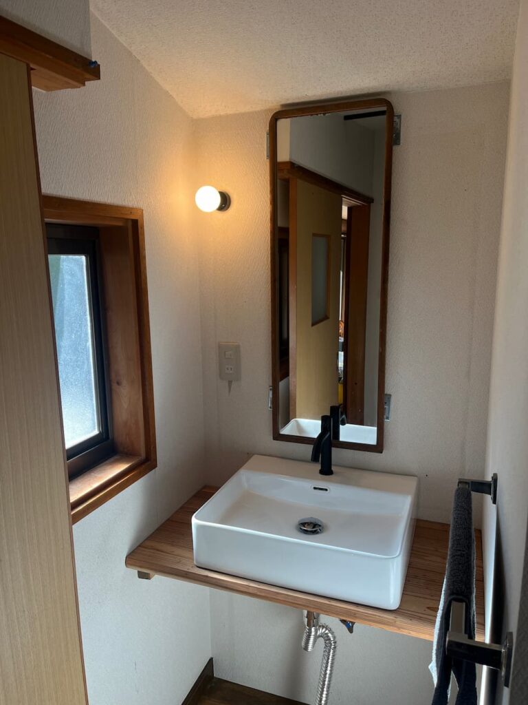 かんぬしの宿の洗面スペース。木製カウンターと白い洗面ボウル。