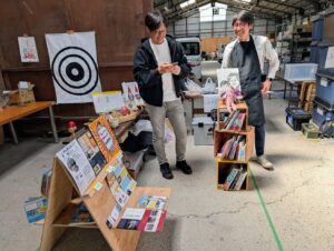 一箱古本市で本を並べ、出店者同士が笑顔で交流している様子